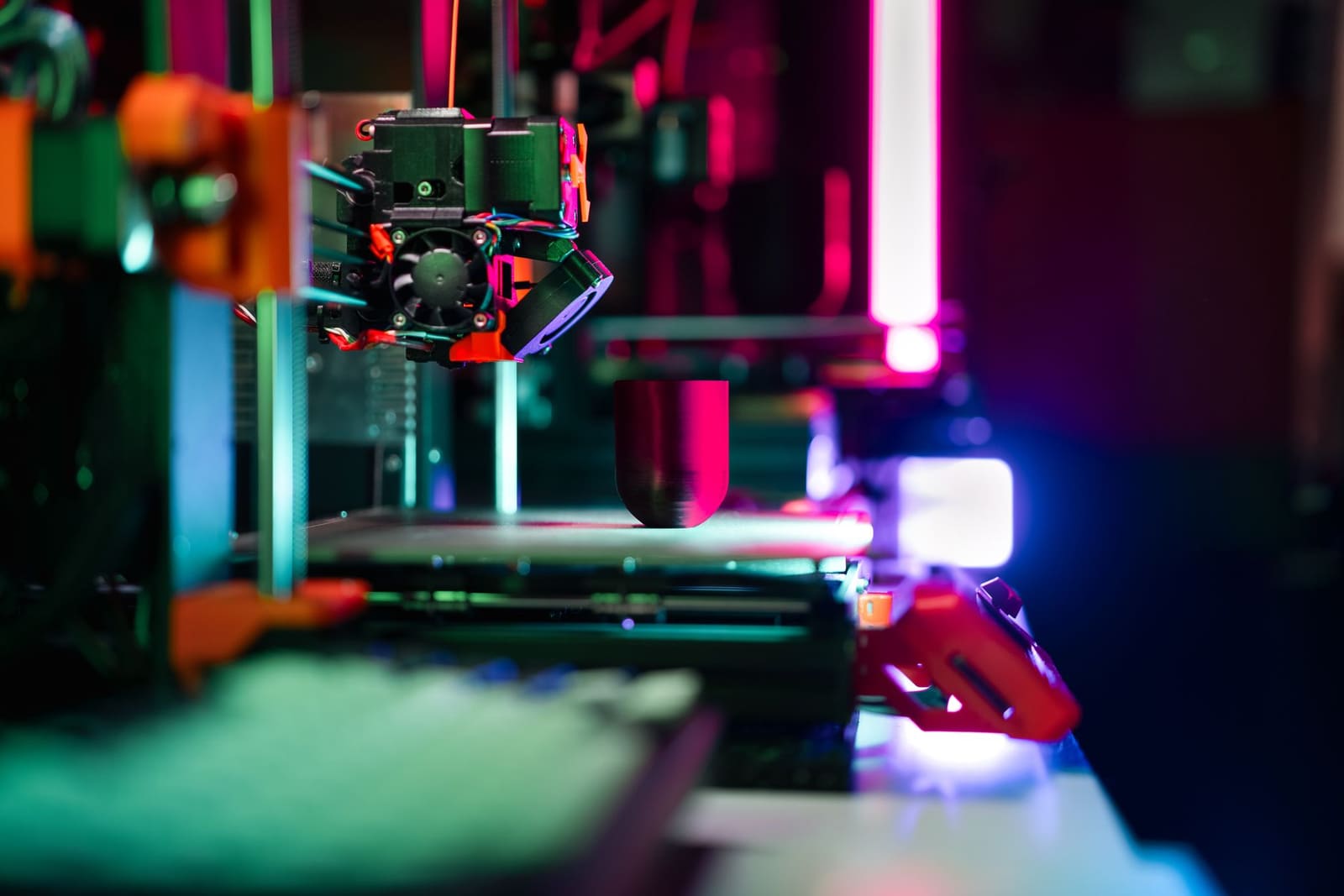 Close-up of a modern 3D printer in a workshop with neon lighting